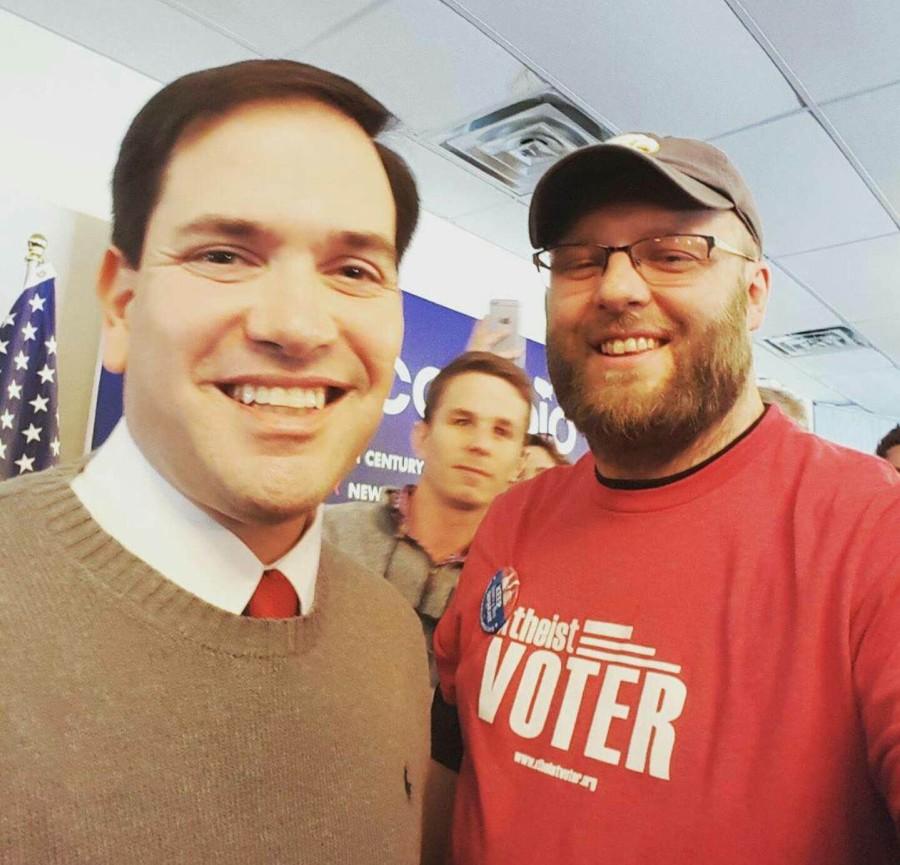 Justin Scott poses for photos with two presidential candidates. He poses with Sen. Marco Rubio while supporting his Atheist VOTER shirt. Scott hopes to work with UNI students to secularize caucus planks