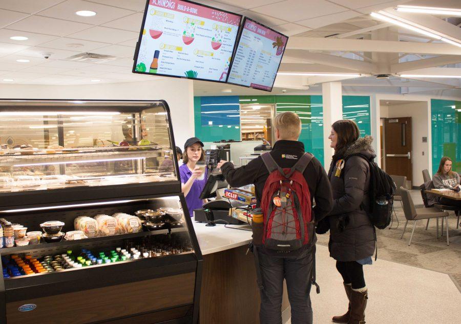 A Schindigs worker hands a student a cup of Sidecar coffee. Schindigs offers a variety of foods including customizable grain bowls, parfaits and other grab and go foods.