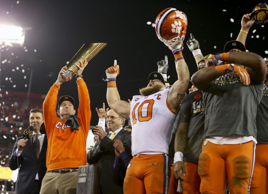 Clemson Tigers head coach Dabo Swinney (left) raises the College Football Playoff National Championship trophy as the team celebrate their  hard-fought victory over the Alabama Crimson Tide.
