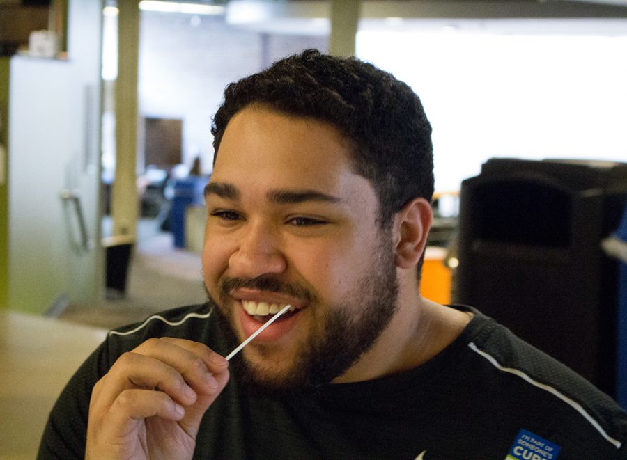 Senior communications major Taylor Peterson swabs his cheek at the Be the Match table in the Union to see if he qualifies to donate bone marrow.