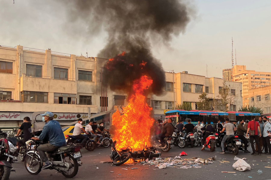 People gathered around a burning motorcycle in Irans capital city, Tehran, on Oct. 8, 2022. 
