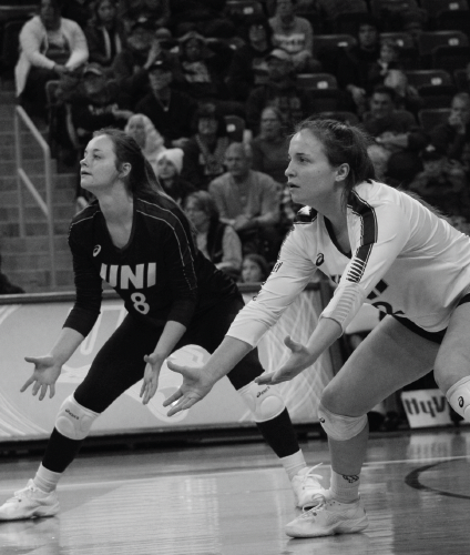 Baylee Petersen (8) stands next to her twin sister Sydney (2), preparing to receive a serve. 