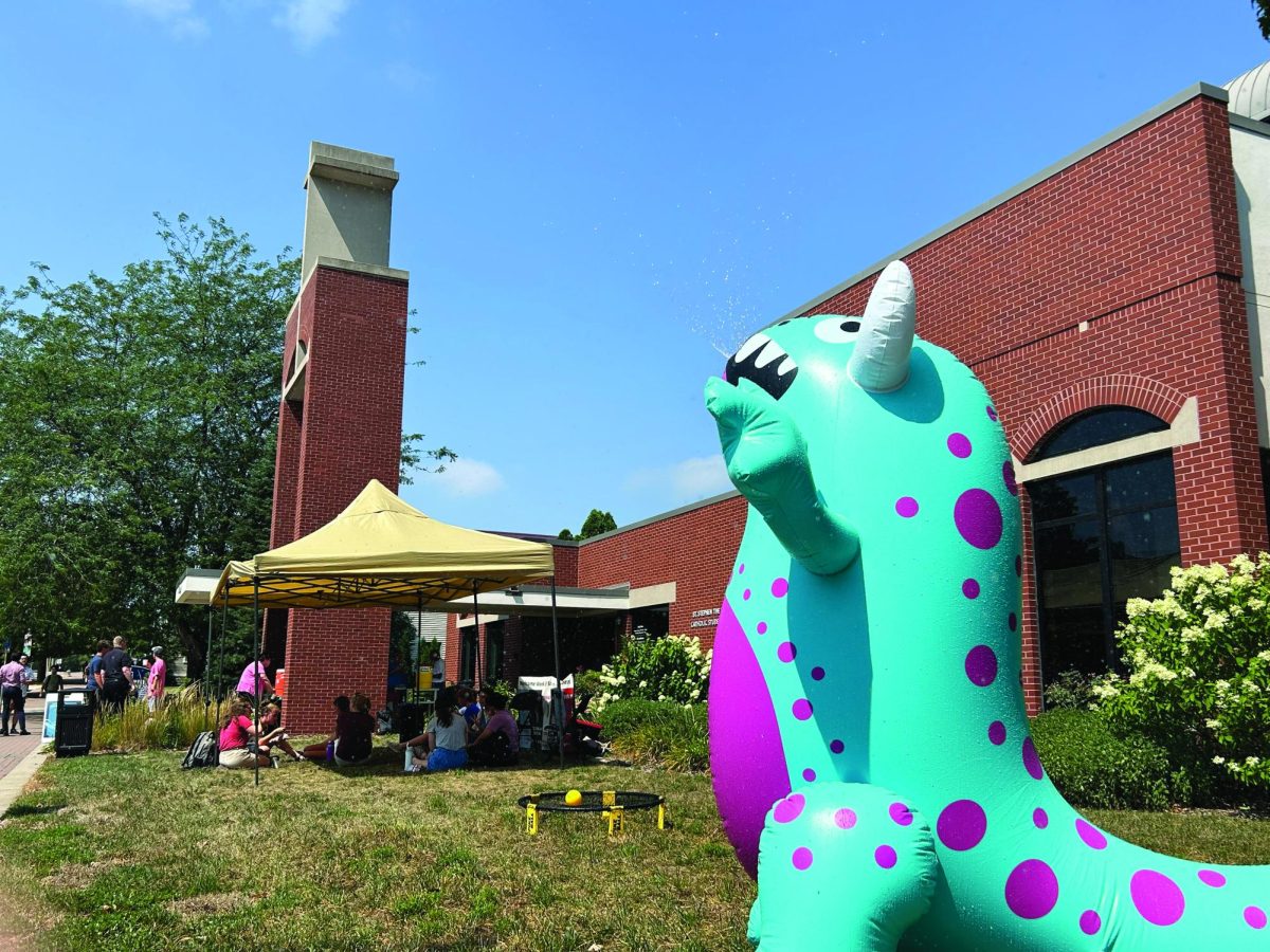 Students catch some relief from the heat in front of St. Stephen the Witness Catholic Student Center on Tuesday by enjoying some walking tacos in the shade and getting misted by an inflatable dinosaur sprinkler.