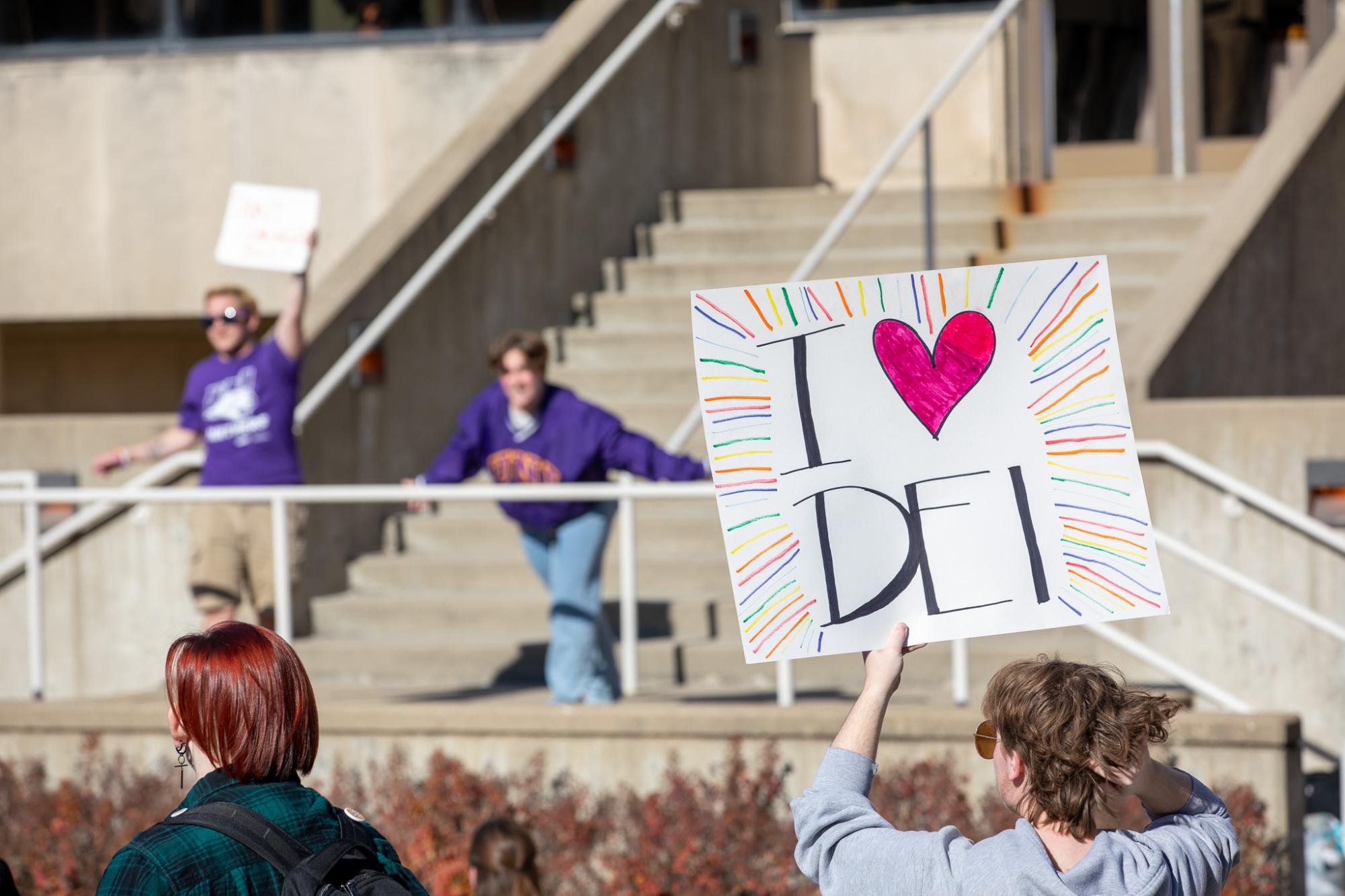 A student holds up a handmade sign in support of Diversity, Equity and Inclusion programs.