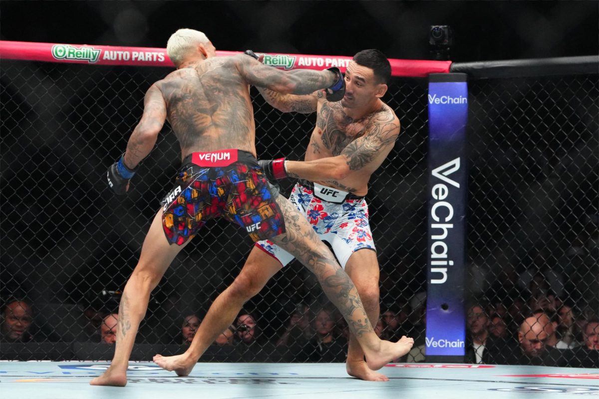 Max Holloway (red gloves) fights Charles Oliveira (blue gloves) during UFC 326 at T-Mobile Arena.